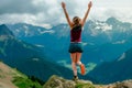 Happy anonymous woman with arms raised jumping over the top of the mountain Royalty Free Stock Photo