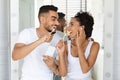 Happy Arab Couple Listening Music On Smartphone And Singing While Brushing Teeth Royalty Free Stock Photo