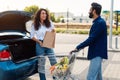 Happy arab couple packing grocery bags into a car trunk at a parking lot, lady looking and talking with her boyfriend Royalty Free Stock Photo