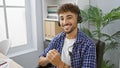 Happy arab man with confident smile, working in business, graces his office space, bossing about wearing headset to aid customer