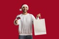 Happy Arab Man Wearing Santa Hat Holding Paper Bag And Credit Card Royalty Free Stock Photo