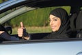 Happy arab saudi woman driving a car with thumb up