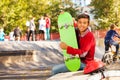 Happy Arabian boy with green skateboard sitting Royalty Free Stock Photo