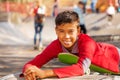 Happy Arabian boy in red shirt lays on skateboard Royalty Free Stock Photo