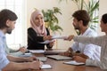 Diverse teammates submitting reports to smiling company boss at office.