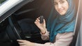 Happy arabian woman holding car key in new vehicle