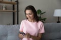 Happy Arabian woman using smartphone, having fun, sitting on couch