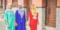 Happy arabic friends walking in city center with traditional islamic clothes - Young arabian women having fun together -