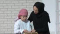 Happy Arabic mother and son together sitting on the couch and reading a book Royalty Free Stock Photo