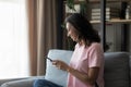 Smiling Arabic woman relax on couch using smartphone