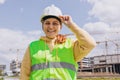 Happy Architect is posing at a construction site. Portrait of successful woman constructor wearing white helmet and Royalty Free Stock Photo
