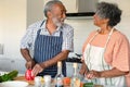 Happy arfican american senior couple cutting vegetables and preparing meal together Royalty Free Stock Photo