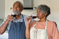 Happy arfican american senior couple drinking wine together in kitchen Royalty Free Stock Photo