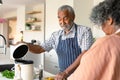 Happy arfican american senior couple preparing meal together and using laptop Royalty Free Stock Photo