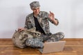 Happy army soldier having video call over laptop and waving to someone