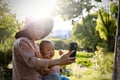 Happy Asia Chinese little boy toddler child play with his mother mom have fun outdoor in a park look at phone carefree childhood Royalty Free Stock Photo