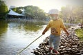 Happy Asia Chinese little boy toddler child play by lake holding string net catch fish carefree childhood parent-child activity Royalty Free Stock Photo