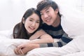 Happy Asia couple teasing each other on the bed in the bedroom.