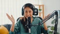 Happy asia girl record a podcast with headphones and microphone look at camera talk and take a rest in her room. Female podcaster
