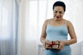 Happy Asia Woman Holding brown Gift Box with Love and Anticipation in Her Bedroom