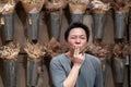 Happy Asian Adult man gives and sends kiss sign by two fingers to the camera in front of vertical dried flower in aluminum pot on