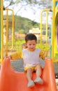 Happy asian baby boy enjoy playing slider in playground in the park Royalty Free Stock Photo