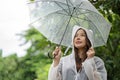 Happy Asian beautiful woman holding umbrella in raining season while standing in the park. Lifesyle Concept