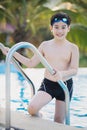 Happy asian boy in swimsuit coming up the pool