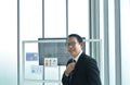 Happy Asian business man holding necktie prepare to present in office room Royalty Free Stock Photo