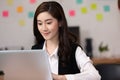 Happy Asian business woman in casual working with laptop and smile looking at camera at modern office Royalty Free Stock Photo