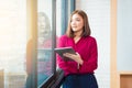 Happy asian business woman standing by large window holding her Royalty Free Stock Photo