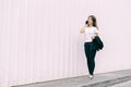 Happy Asian business woman walking and talking smart phone on street in city with white color wall background