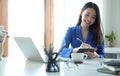 Happy asian business woman working with laptop computer and making notes on notebook Royalty Free Stock Photo