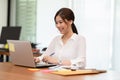 Happy Asian business woman working with laptop and smile looking at camera at modern office Royalty Free Stock Photo