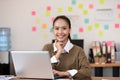 Happy Asian business woman working with laptop and smile looking at camera at modern office or Co-Working Space Royalty Free Stock Photo