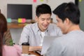 Happy Asian business young man smile and working with laptop and their team in co-working space or modern office Royalty Free Stock Photo