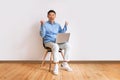 Happy asian businessman sitting on chair with laptop, raising hands up, excited over business success, full length Royalty Free Stock Photo