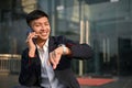 Happy Asian businessman talking on the phone and checking the time on his watch Royalty Free Stock Photo