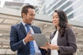 Happy Asian businessmen discussing with female boss in the city. Male open application in tablet showing data to present work