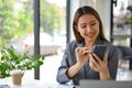 Happy Asian businesswoman chatting with her friend on her phone at her office desk Royalty Free Stock Photo