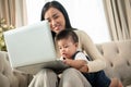 A happy Asian businesswoman mom is working from home and taking care of her naughty baby boy Royalty Free Stock Photo