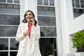 Happy Asian businesswoman talking on the phone while walking outside of the building Royalty Free Stock Photo