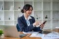 A happy Asian businesswoman using her smartphone at her desk in her private office Royalty Free Stock Photo