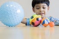 Happy Asian child boy sitting on chair playing colorful baby ball toy and having fun Royalty Free Stock Photo