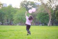 A happy Asian child with colorful toy balloons outside the house. Smiling child having fun in green spring field on blue sky Royalty Free Stock Photo