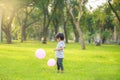 A happy Asian child with colorful toy balloons outside the house. Smiling child having fun in green spring field on blue sky Royalty Free Stock Photo