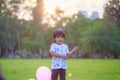 A happy Asian child with colorful toy balloons outside the house. Smiling child having fun in green spring field on blue sky Royalty Free Stock Photo