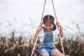 Asian child girl having fun to play on wooden swings in playground with beautiful nature