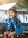 Happy asian child girl having fun to play on wooden swings in playground