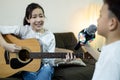 Happy asian child girl,kid boy singing a song together at home,family concert,sister plays the guitar,little brother hold a Royalty Free Stock Photo